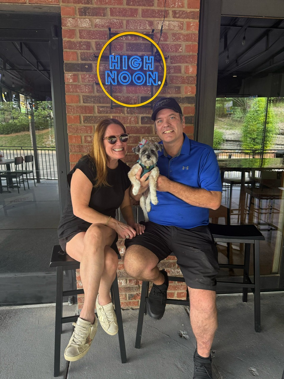 Owners with their dog on the patio at Rippy's, under the High Noon sign